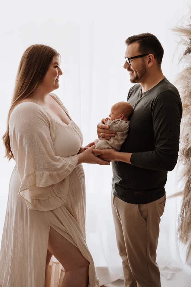 Eltern stehen sich gegenüber und halten ihr Baby zwischen sich