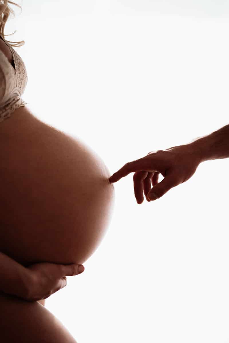 Hand zeigt auf nackten Babybauch