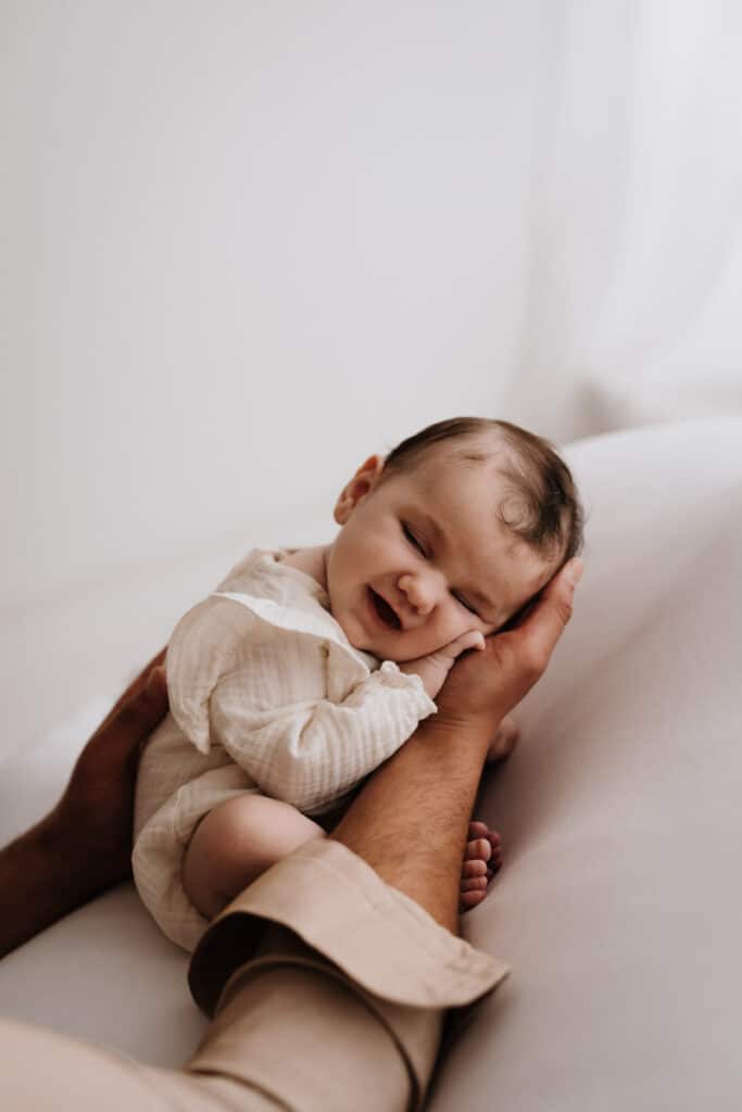 Baby liegt in Papas Händen und lächelt