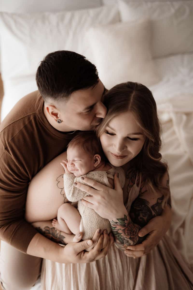 Eltern kuscheln mit Baby im Arm