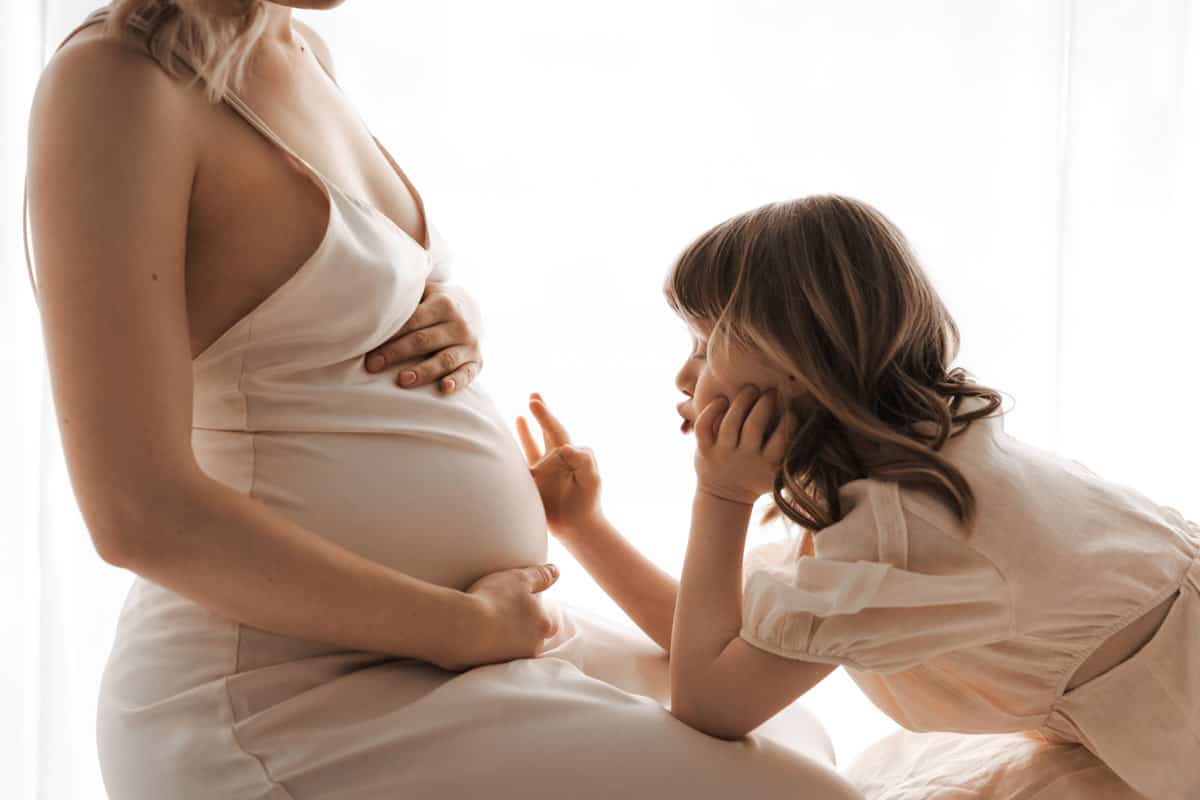 Kind malt mit Fingern auf dem Babybauch ihrer Mama