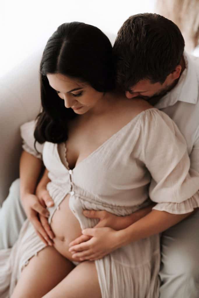 Mann und seine schwangere Freundin kuscheln und halten den Babybauch