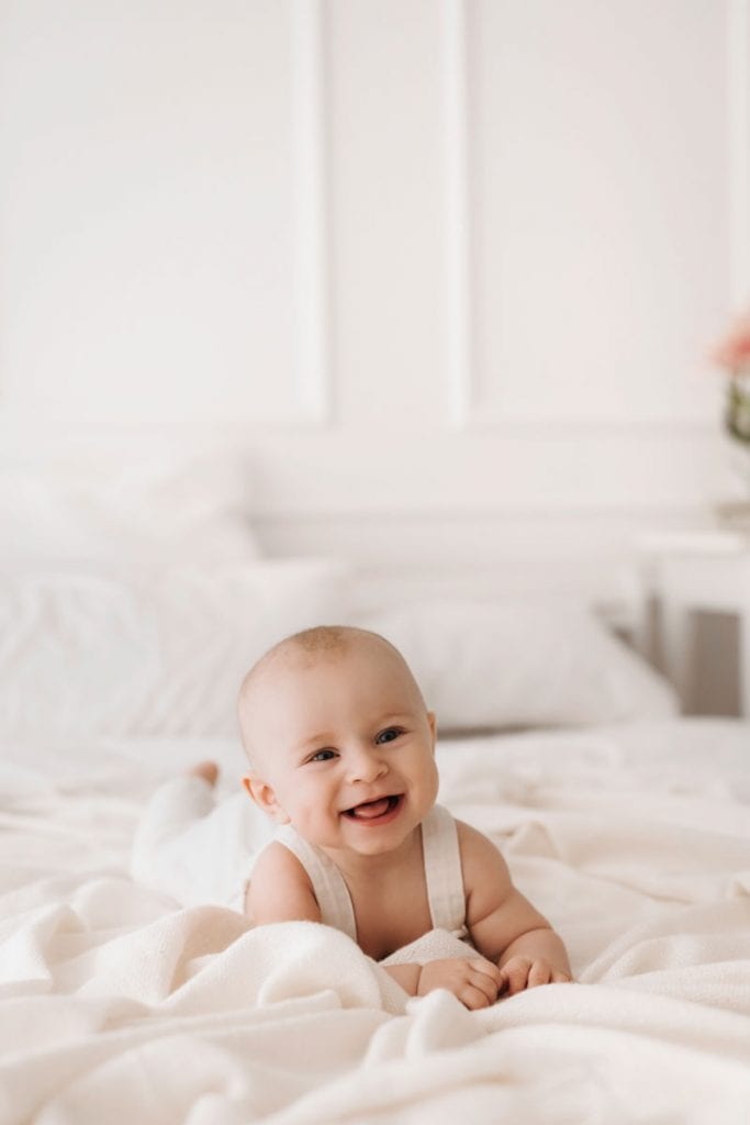Ein Baby liegt lachend auf dem Bauch