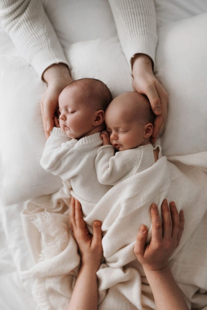 Neugeborene Zwillinge werden von Mamas und Papas Händen gehalten