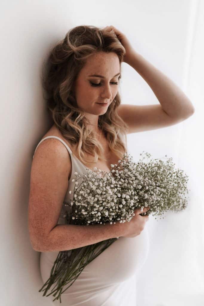 Schwangere mit Blumen im Arm